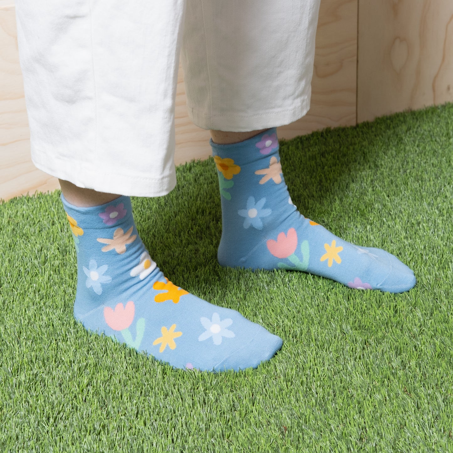Woman wearing luxurious sky blue ankle socks with fun cute multi color floral patterns with white pants