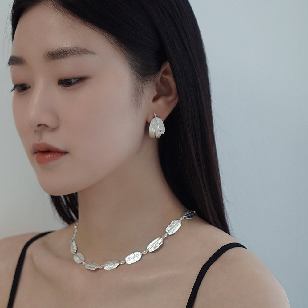 An Asian Korean woman wearing two Acacia leaf handmade silver earrings and acacia leaf silver handmade necklace