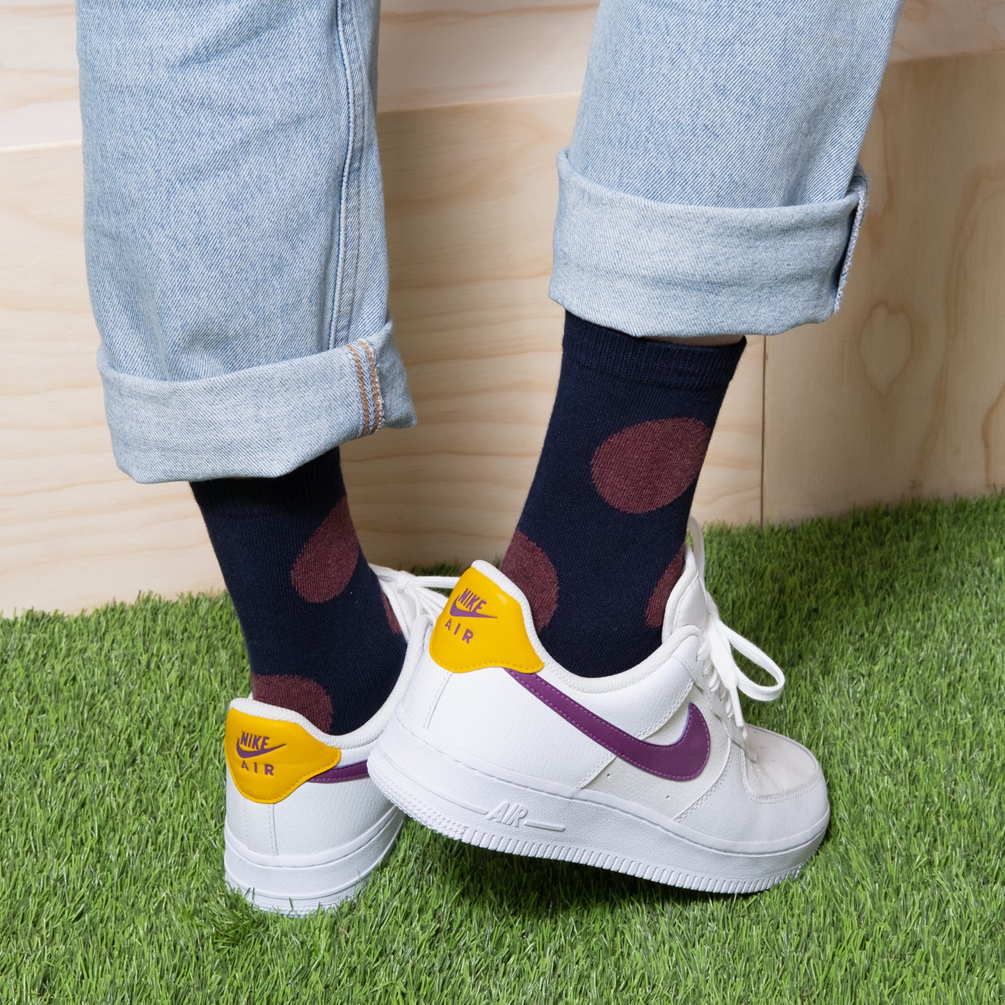 Back view of a woman wearing a stylish outfit featuring navy socks with red polka dots and white sneakers