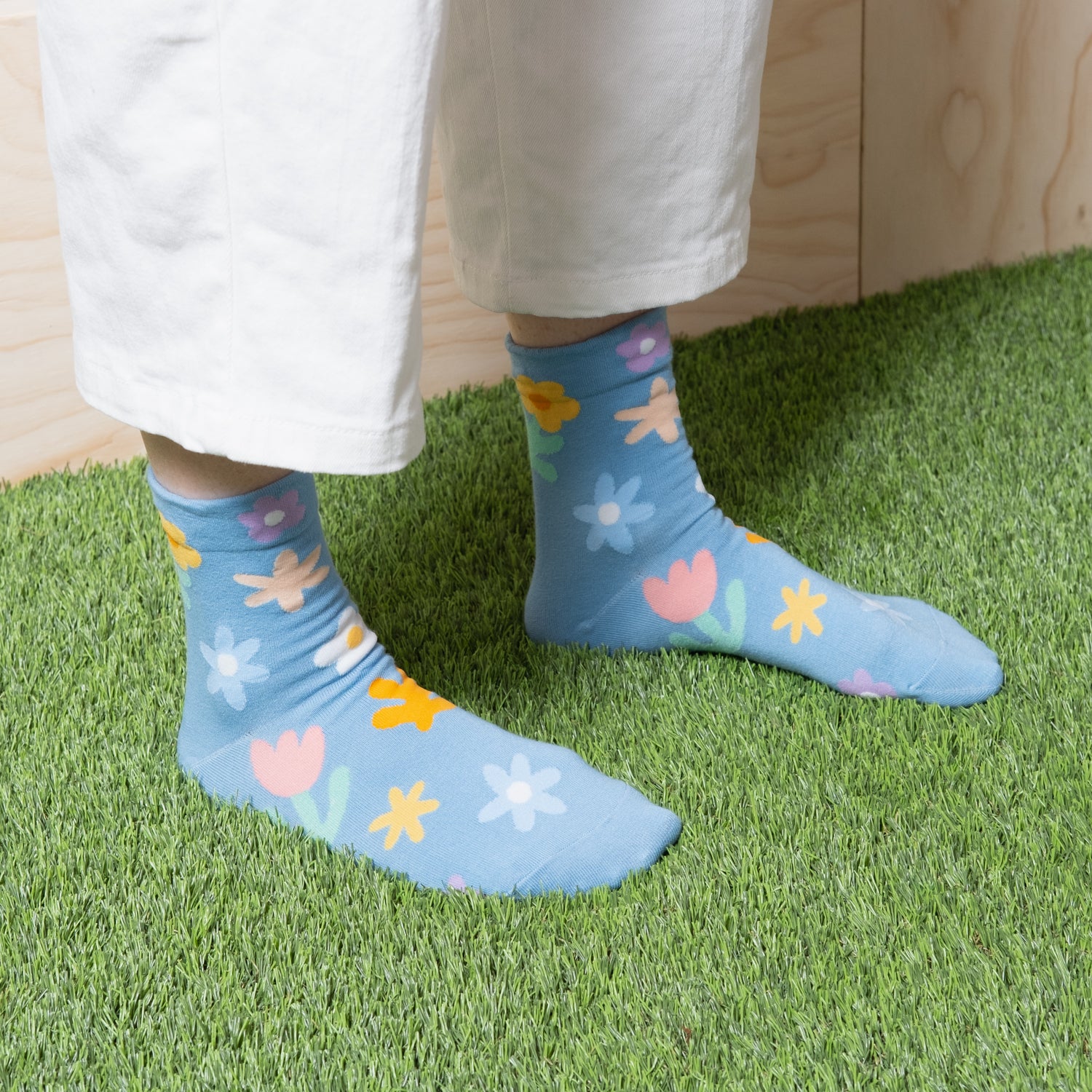 Woman wearing luxurious sky blue ankle socks with fun cute multi color floral patterns with white pants 