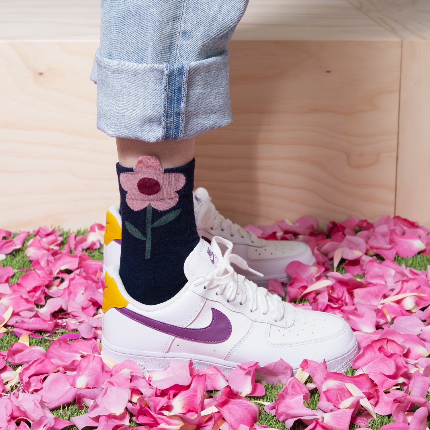 Playful look with navy blue ankle socks, pink flower with white sneakers, and jeans