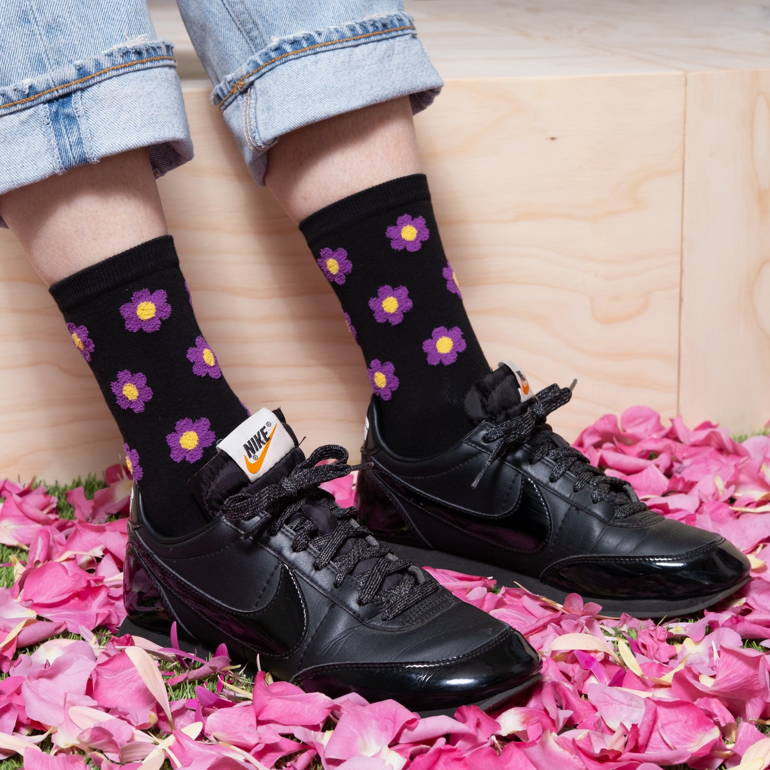 woman wearing luxurious black ankle sock with purple floral dots pattern with black nike sneakers and jeans