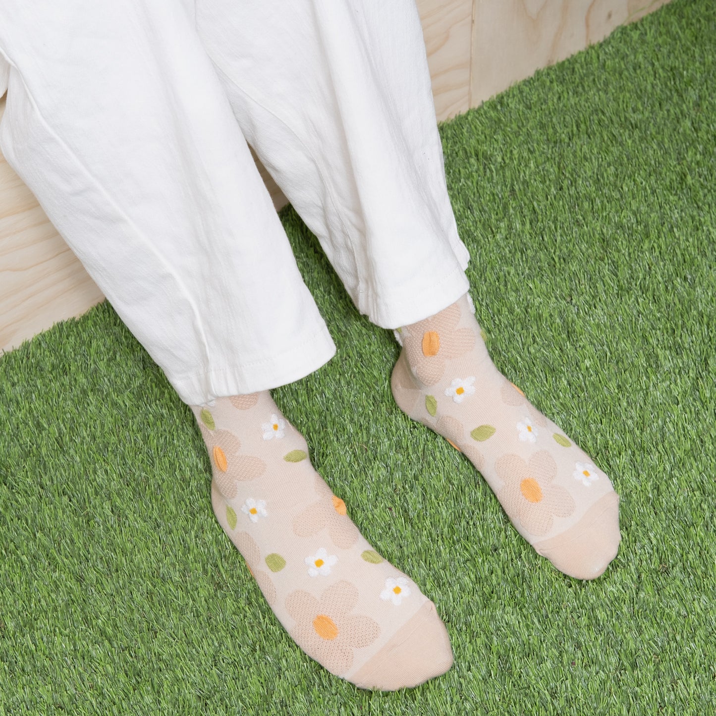 Woman wearing ivory white textured floral mesh socks with white pants