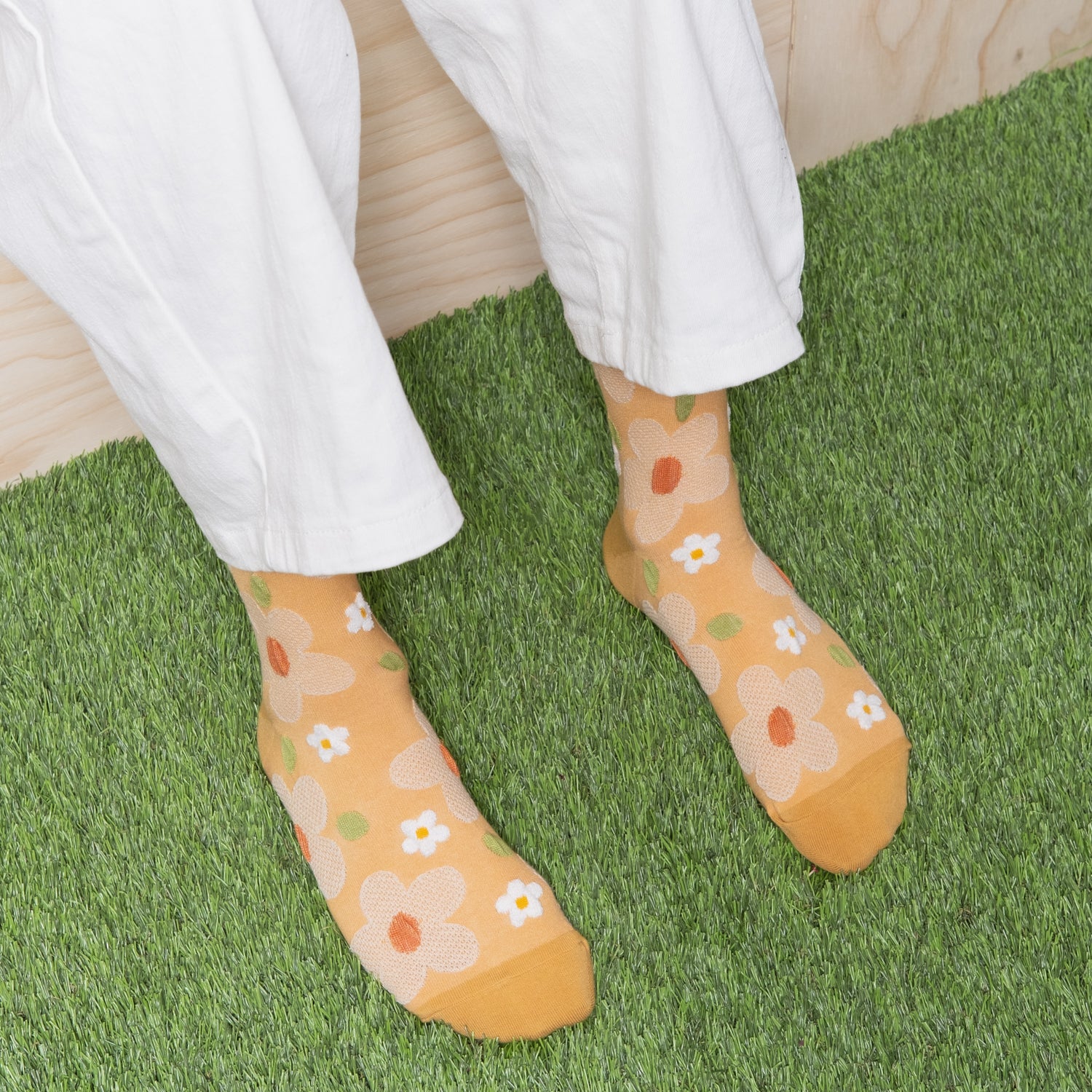 Woman wearing soft yellow textured floral socks with white pants