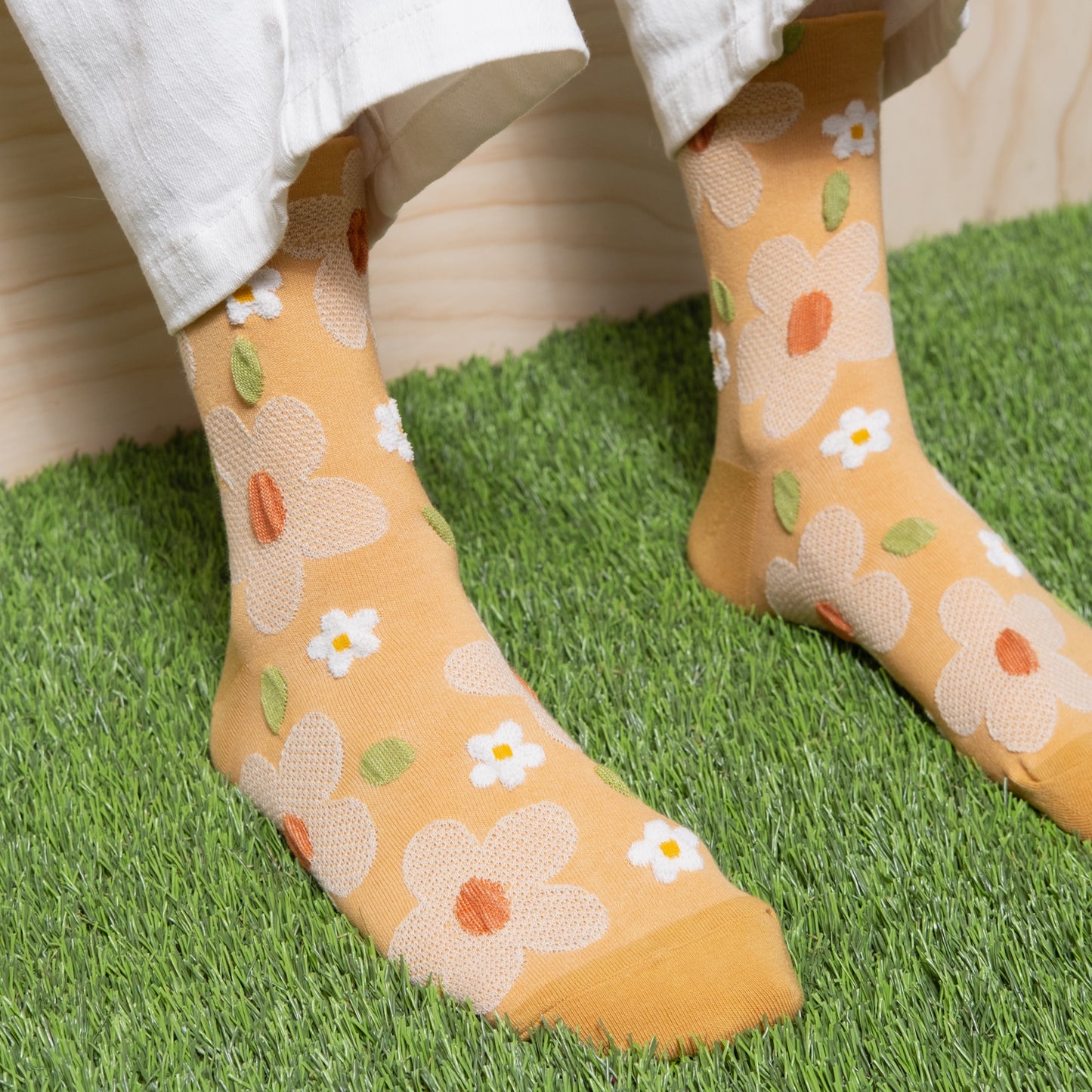 detail view of Woman wearing soft yellow textured mesh floral socks with white pants