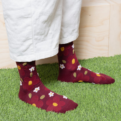 Woman wearing dark red textured floral socks with white pants